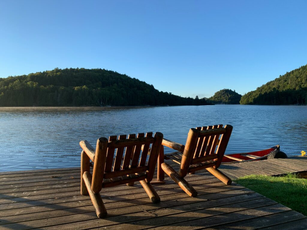 Two chairs on a dock overlooking a lake and mountains.