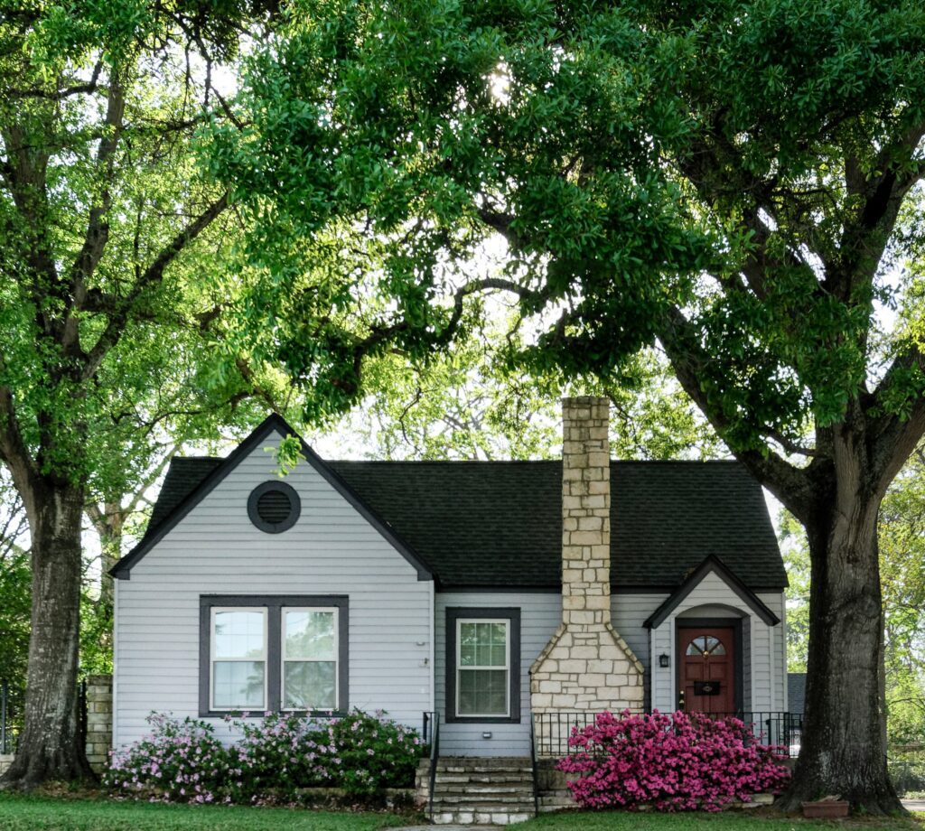 White house with a brick chimney and trees.