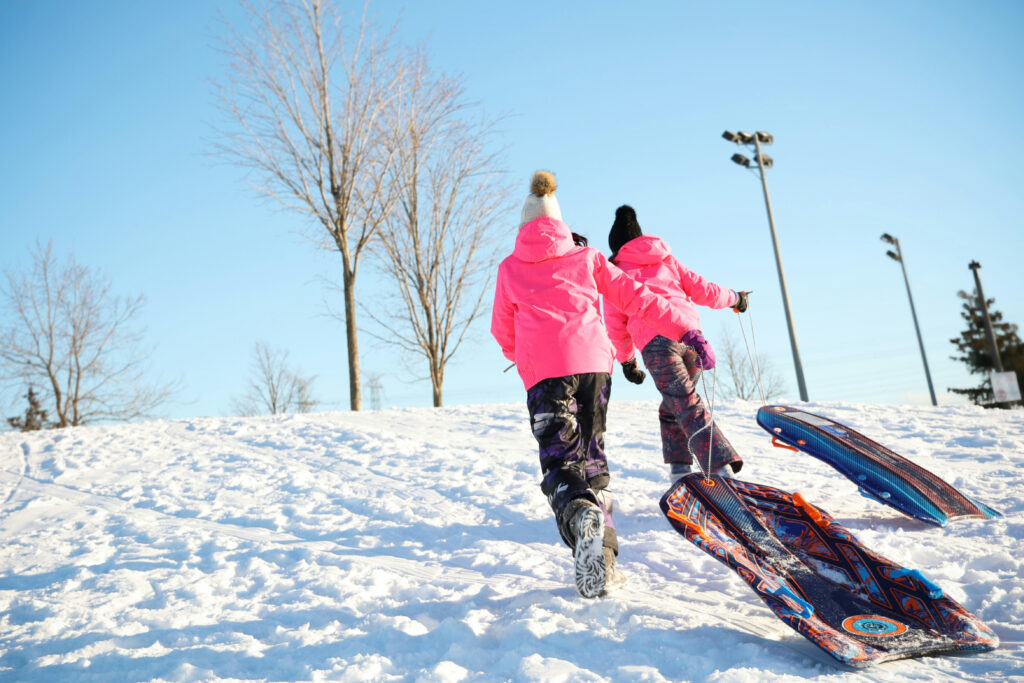 Kids with sleds climbing a snow covered mountain.