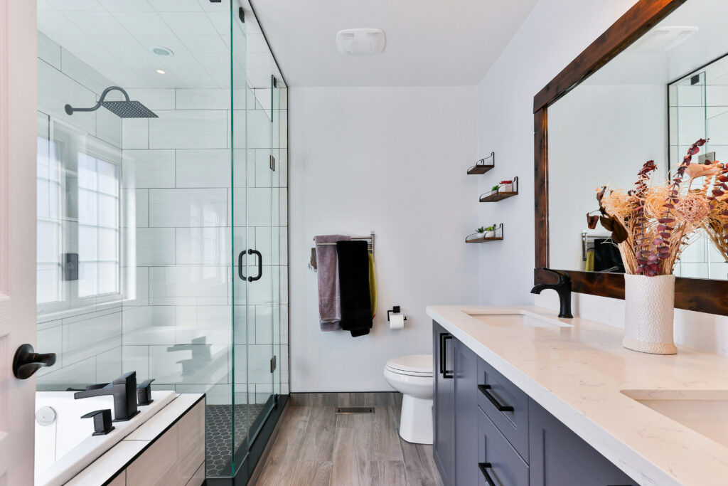 A renovated bathroom with double sink, glass shower and soaking tub.